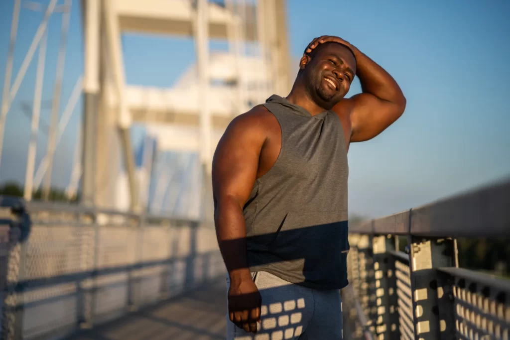 athletic man enjoying sunny day on bridge utc